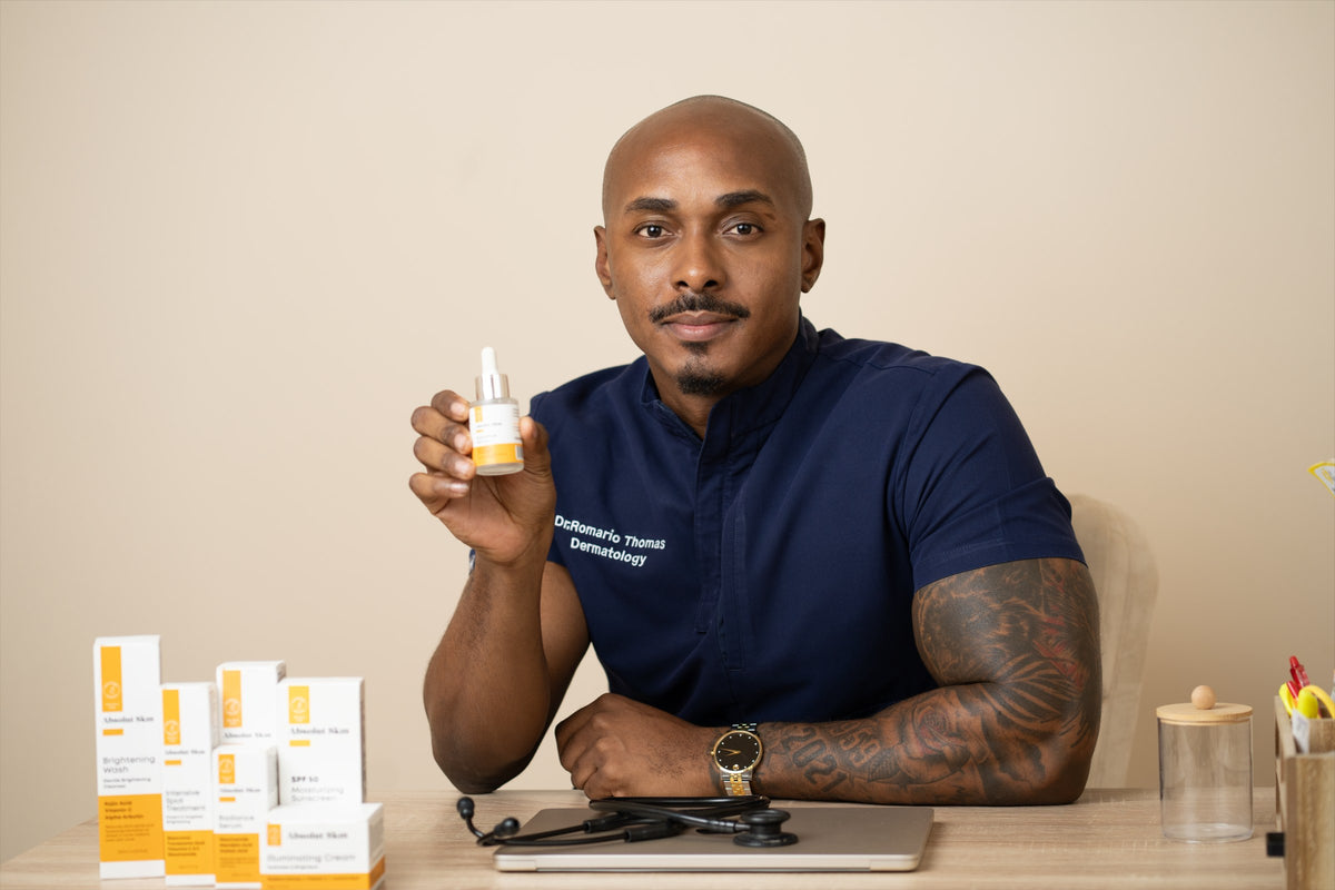 Dr. Romario Thomas, Founder and Dermatologist, holding an Absolut Skin product